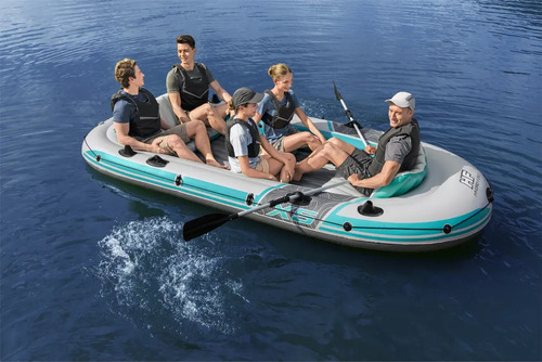 Bote inflable turquesa con cinco personas sentadas en el agua