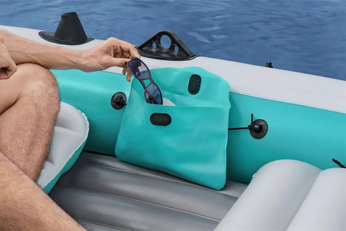 Persona sosteniendo gafas sobre el tubo lateral turquesa de un bote inflable tipo gomón.