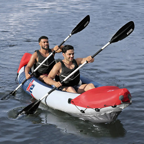 Kayak inflable rojo y blanco con dos personas remando en el agua con remos de doble pala