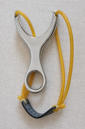Resortera de acero inoxidable con mango amarillo y grip negro, vista frontal