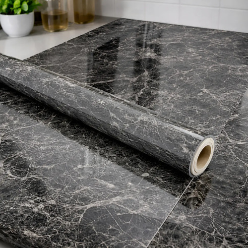 Papel adhesivo de mármol gris grafito parcialmente desenrollado mostrando el ancho y textura del patrón.