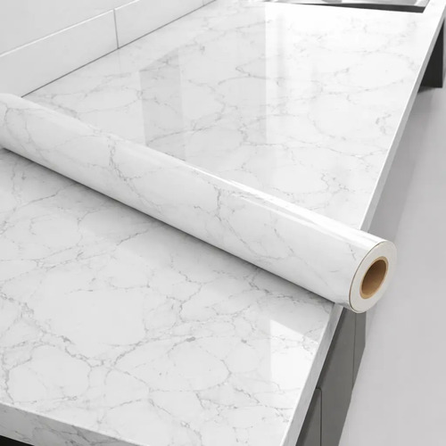 Rollo de papel adhesivo con patrón de mármol blanco siendo desenrollado, mostrando el ancho de 80 cm