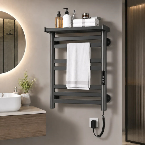 Toallero eléctrico calefactor gris oscuro instalado en pared de baño con toalla blanca y productos de aseo en repisa