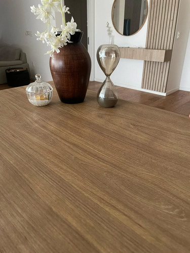 Papel adhesivo madera con textura marrón instalado en escritorio, junto a florero blanco, reloj de arena y espejo redondo.