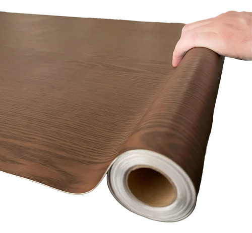 Rollo de papel adhesivo madera marrón siendo desenrollado, mostrando textura y núcleo blanco