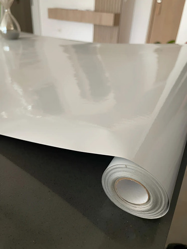 Rollo de papel autoadhesivo blanco liso parcialmente desenrollado sobre superficie oscura