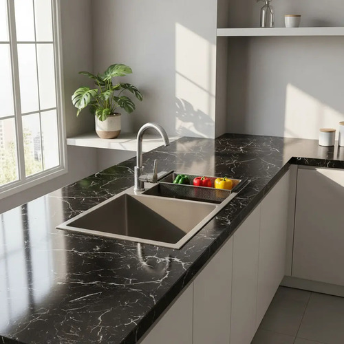 Papel adhesivo mármol negro aplicado sobre encimera de cocina con fregadero y grifo.