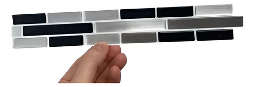 Muestrario de placas autoadhesivas mosaico 3D en grises, negros y plateados, con una placa sostenida en mano.