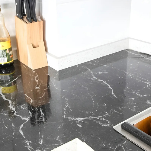 Papel adhesivo mármol negro instalado en encimera de cocina con portacuchillos de madera y botella de aceite