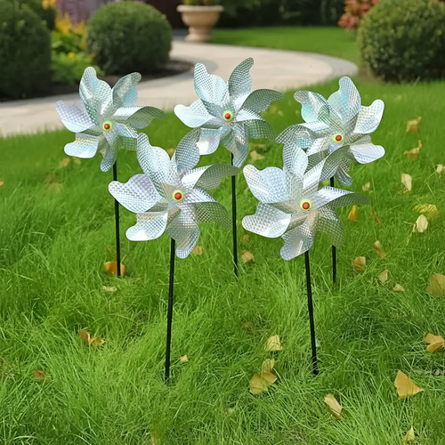 Cinco molinos holográficos blancos con flores de pétalos y centros dorados instalados en varillas sobre césped de jardín